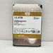 A Western Digital 12.0TB WD Gold internal hard drive, model WD100XBXZ, standing upright against a light gray textured wall.